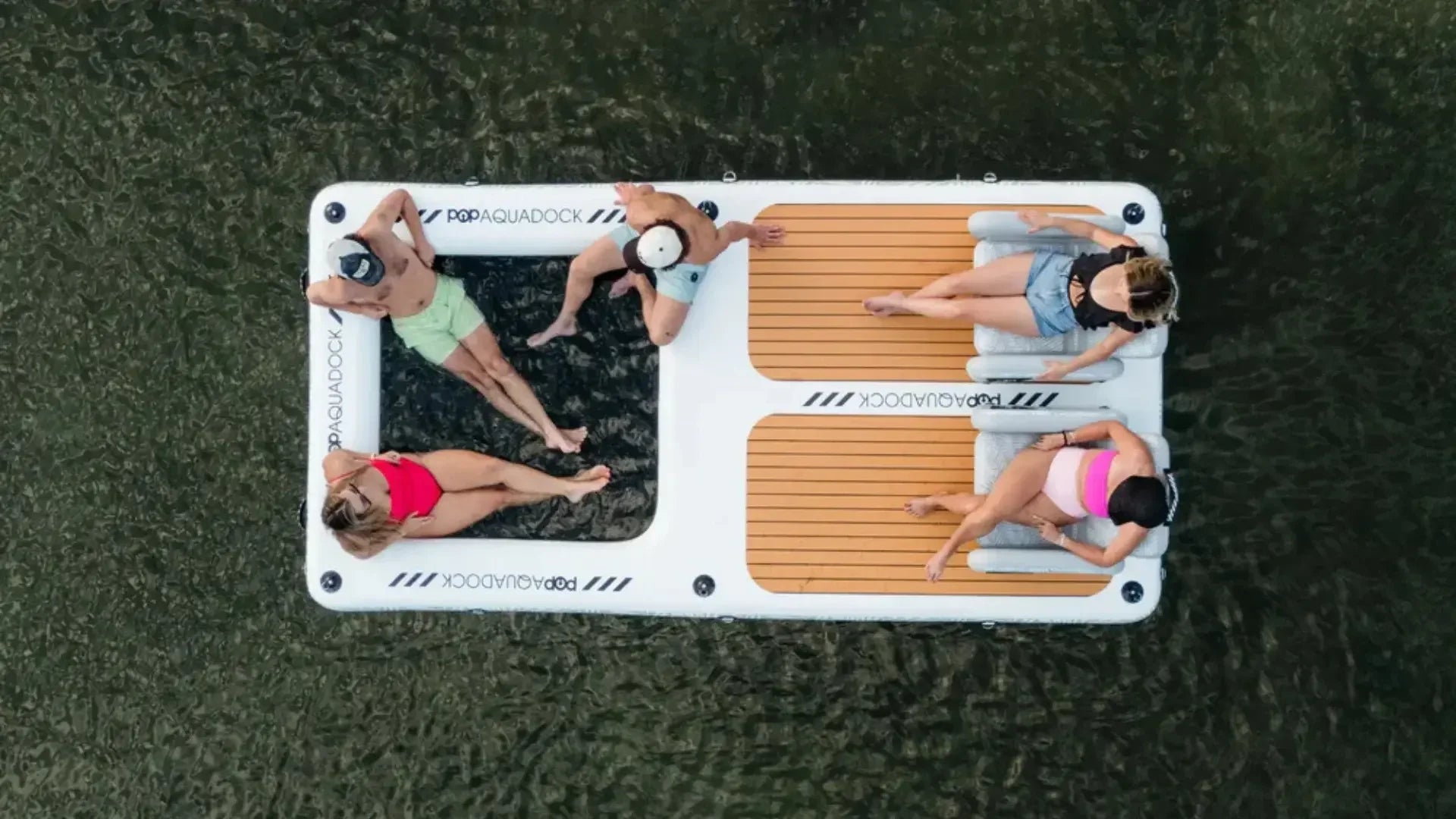 Overhead view of people relaxing on an inflatable floating dock on calm water.