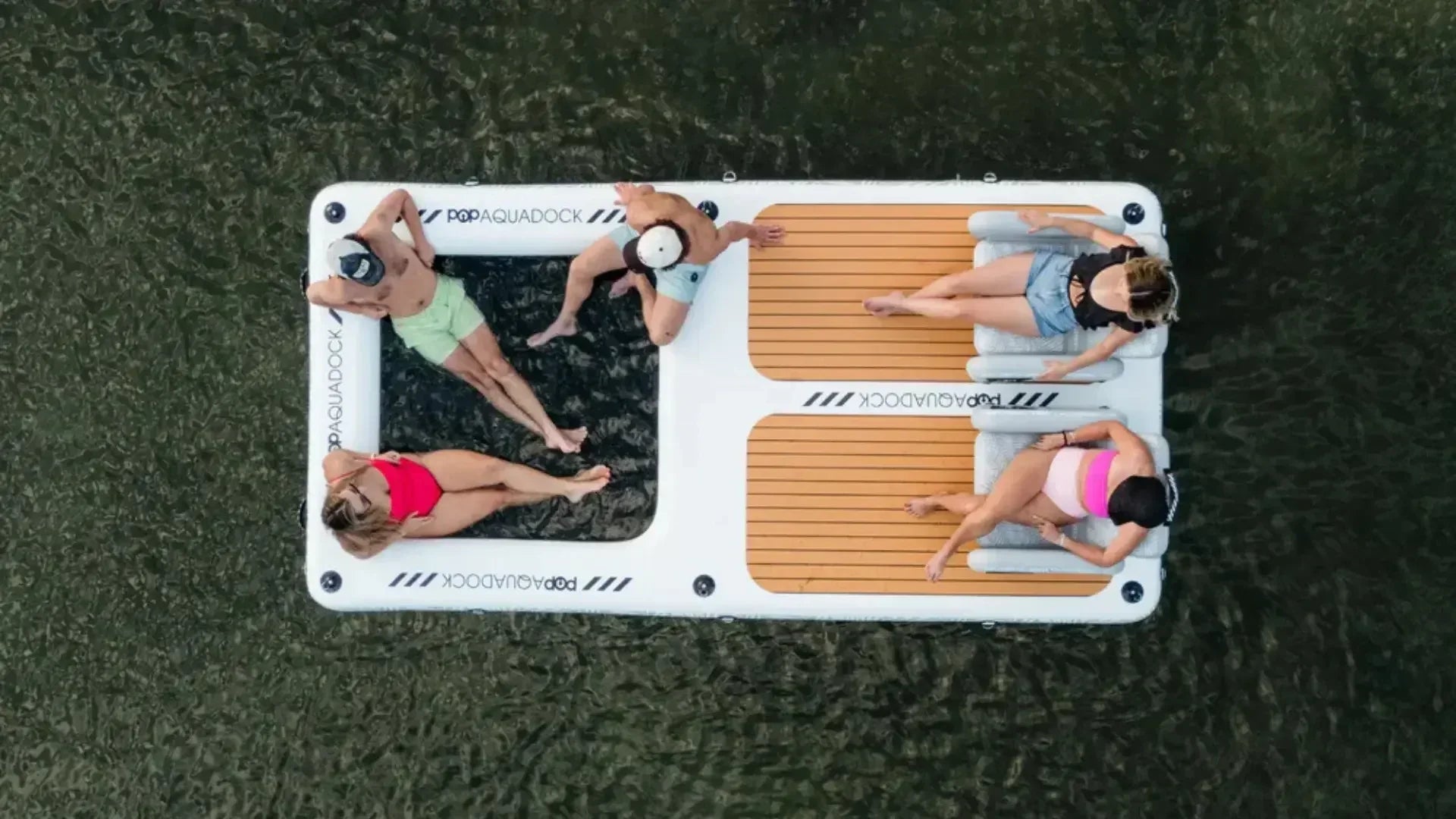 Overhead view of people relaxing on an inflatable floating dock on calm water.