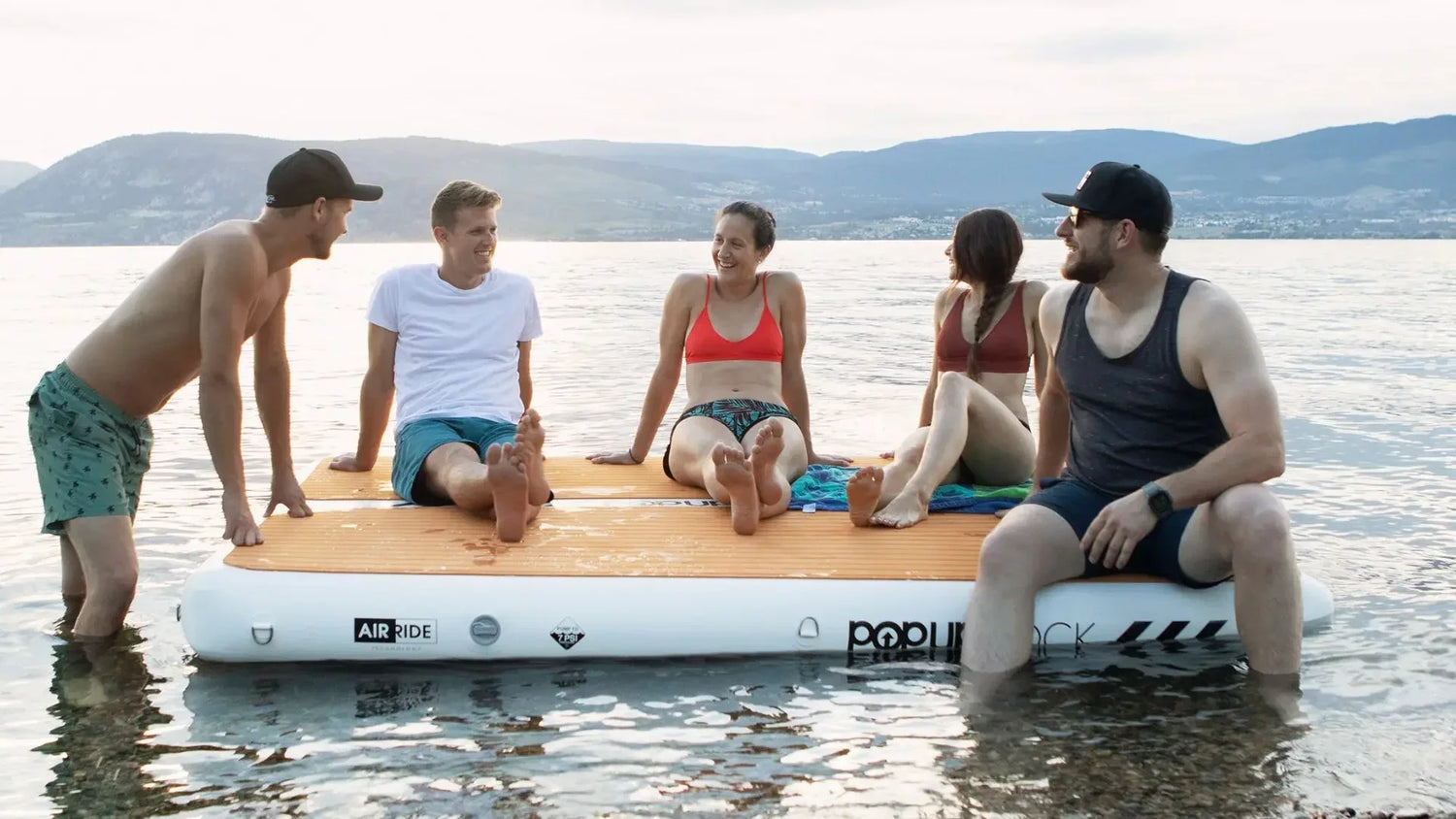 Group of people sitting on an inflatable floating dock relaxing together on calm water.
