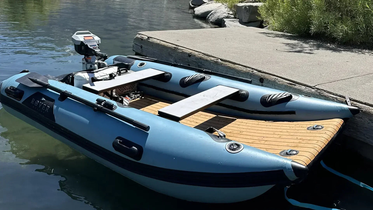 Rover Marine inflatable boat docked at shore showing deck layout, seating, and electric outboard.
