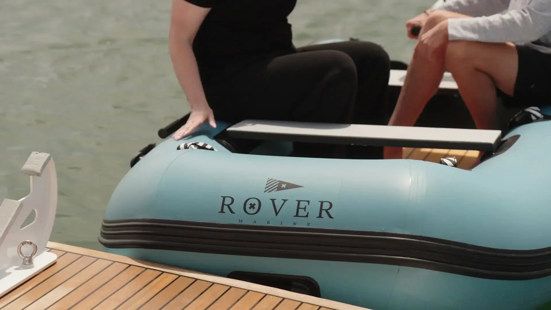 Rover Marine inflatable boat secured alongside a dock with passengers seated onboard.