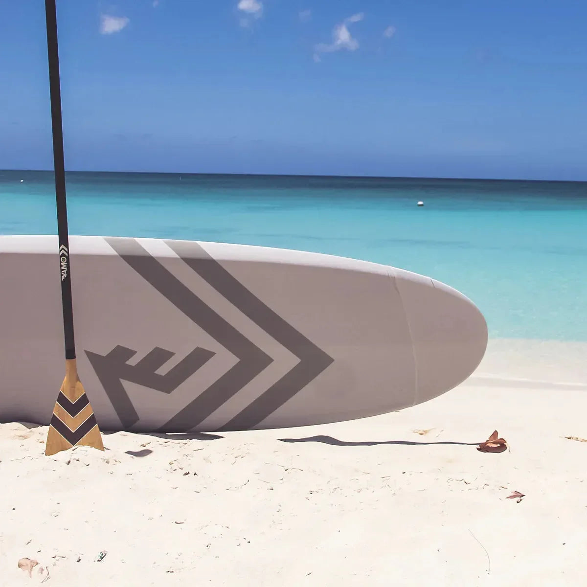 Vamo blem carbon fiber paddle placed on a paddleboard at the beach.