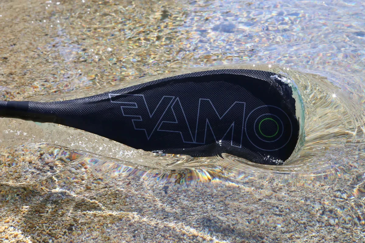 Vamo carbon fiber fixed shaft paddle resting on the beach near lake.