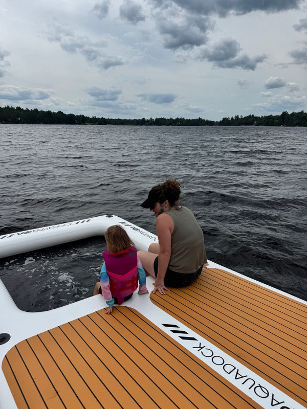 AquaDock owner and child sitting on the edge of the dock on a lake