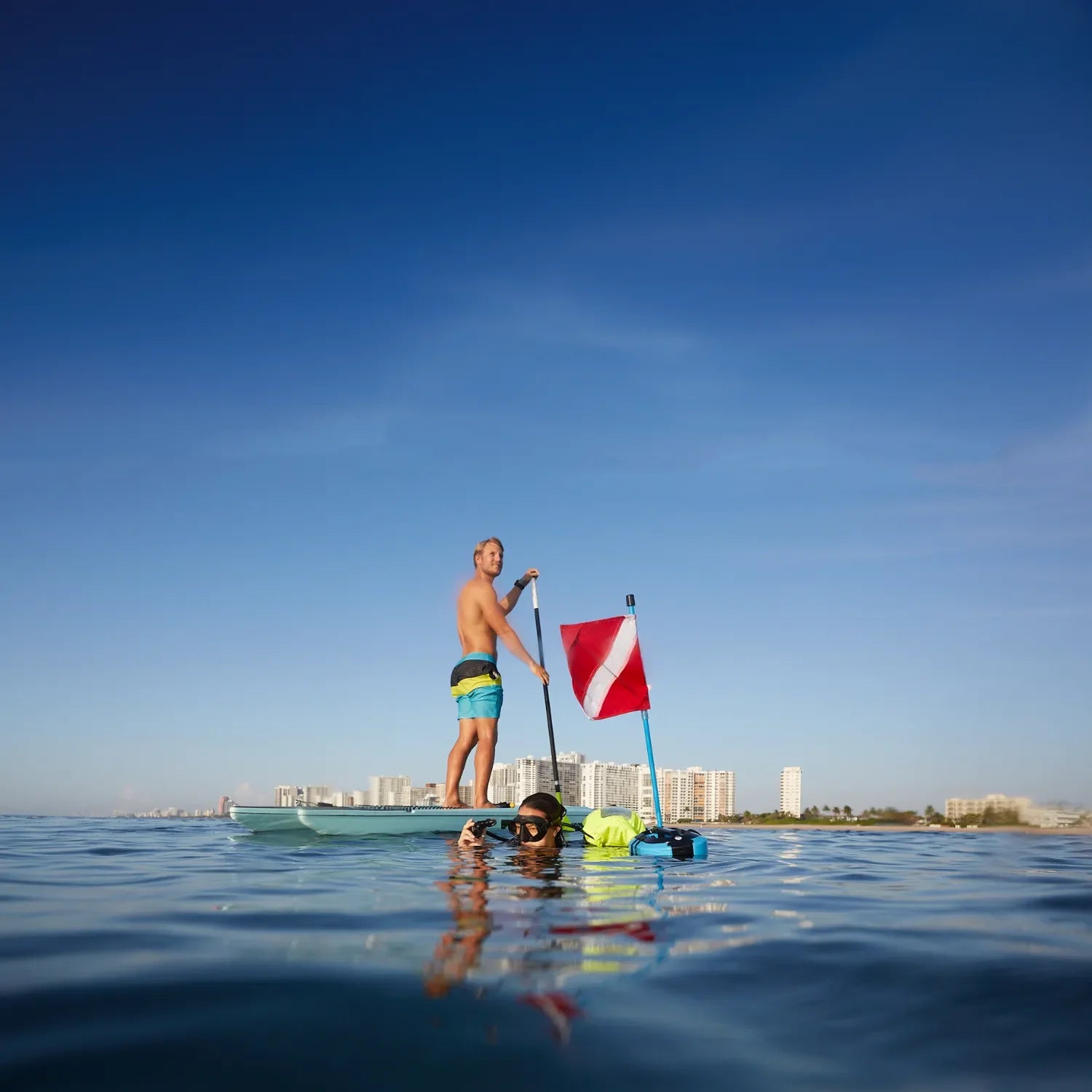 Diver exploring the ocean with DiveBlu3 Nomad floating dive compressor and flag.
