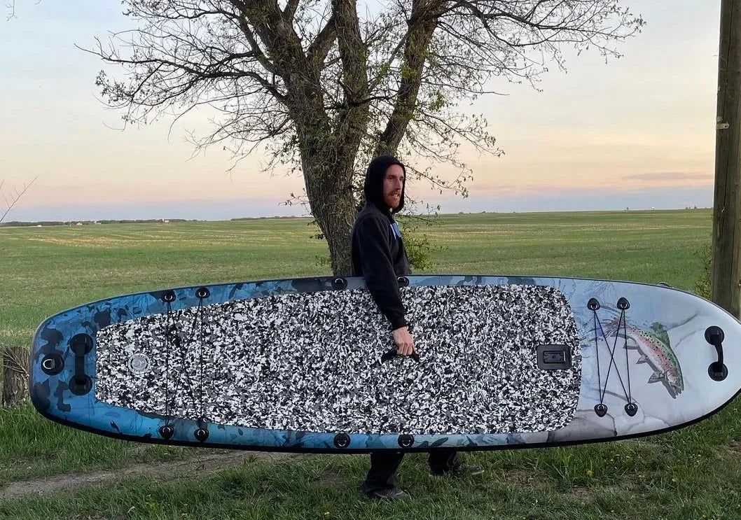 Ionic Hook ‘Em paddleboard standing by tree near lake.