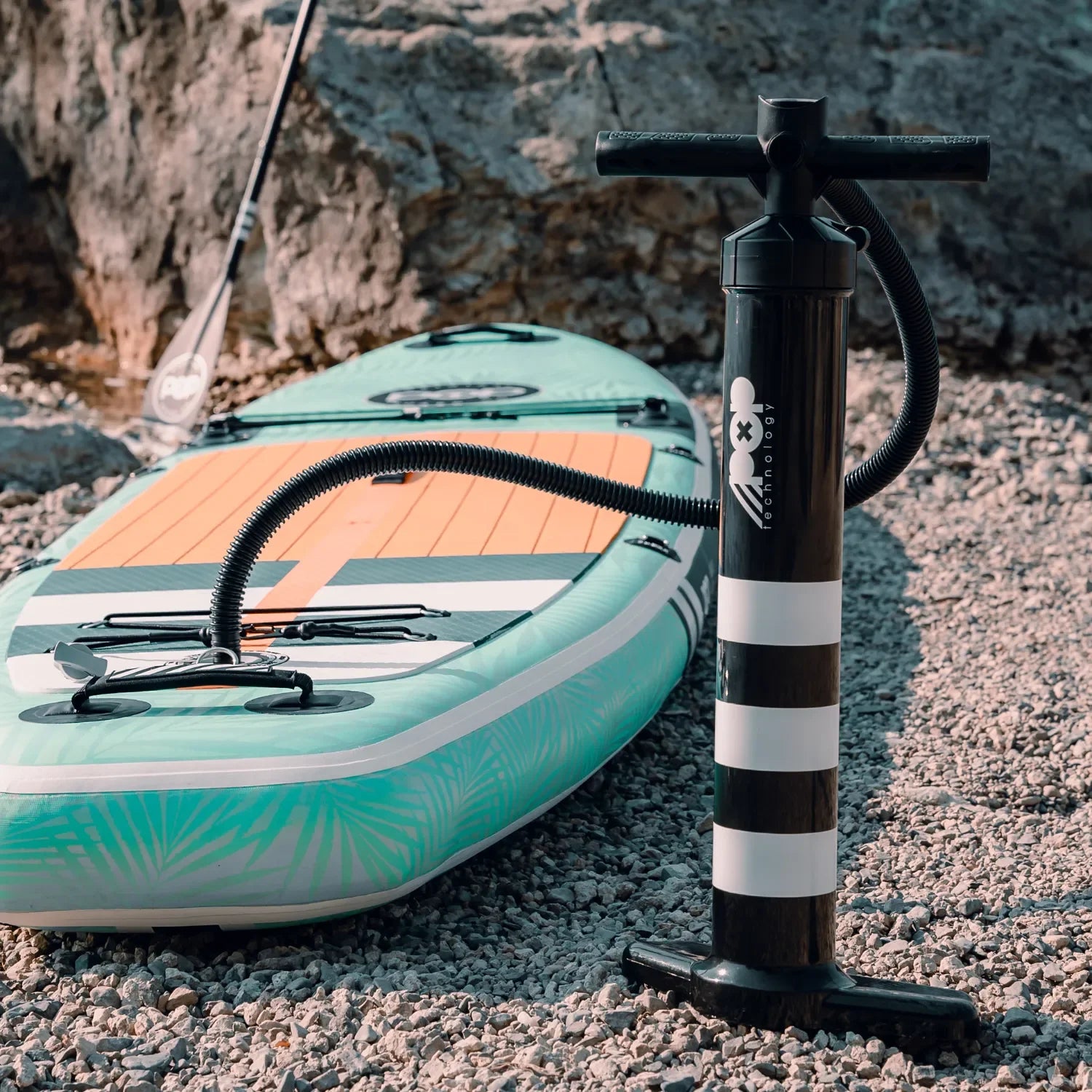 POP Board Co. dual-action hand pump shown beside inflatable paddleboard, part of the Canadian Board Co. SUP package.