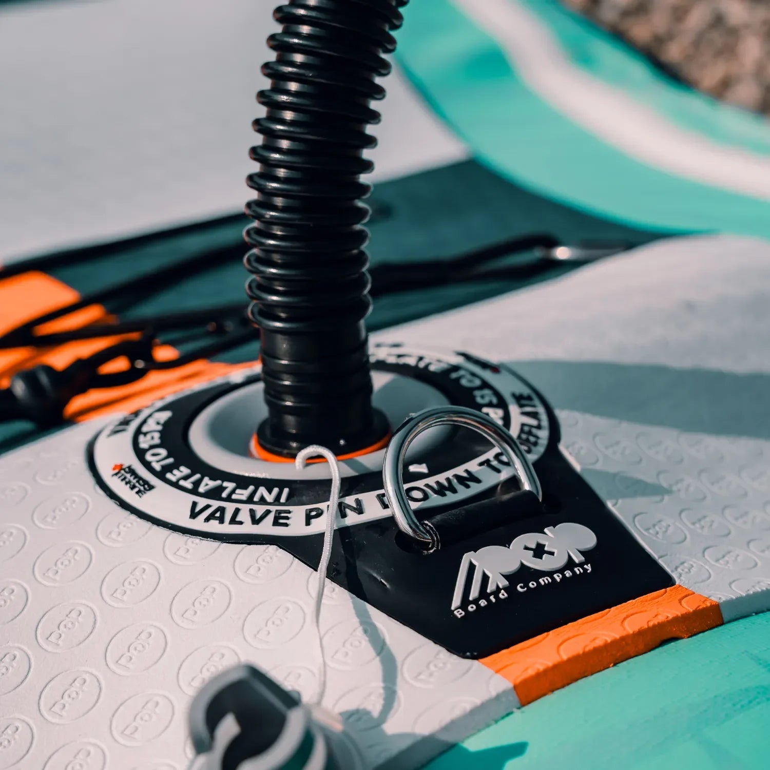 Paddleboard inflation valve connected to pump hose, showing POP Board Co. logo and secure fit, Canadian Board Co. gear.