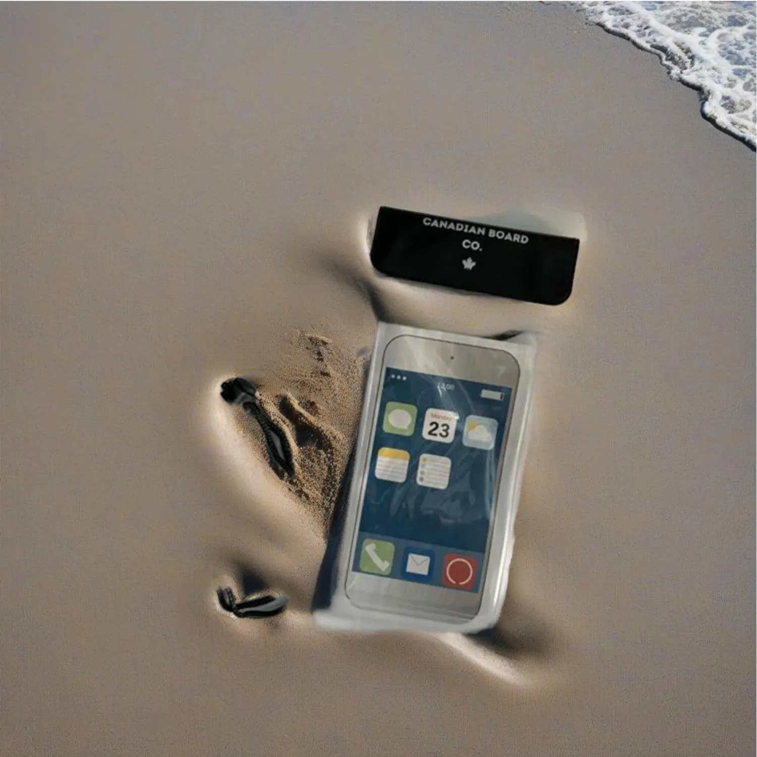 POP Board Co. waterproof phone pouch with smartphone inside, placed on sand with water nearby, ideal for beach and SUP use, Canadian Board Co.