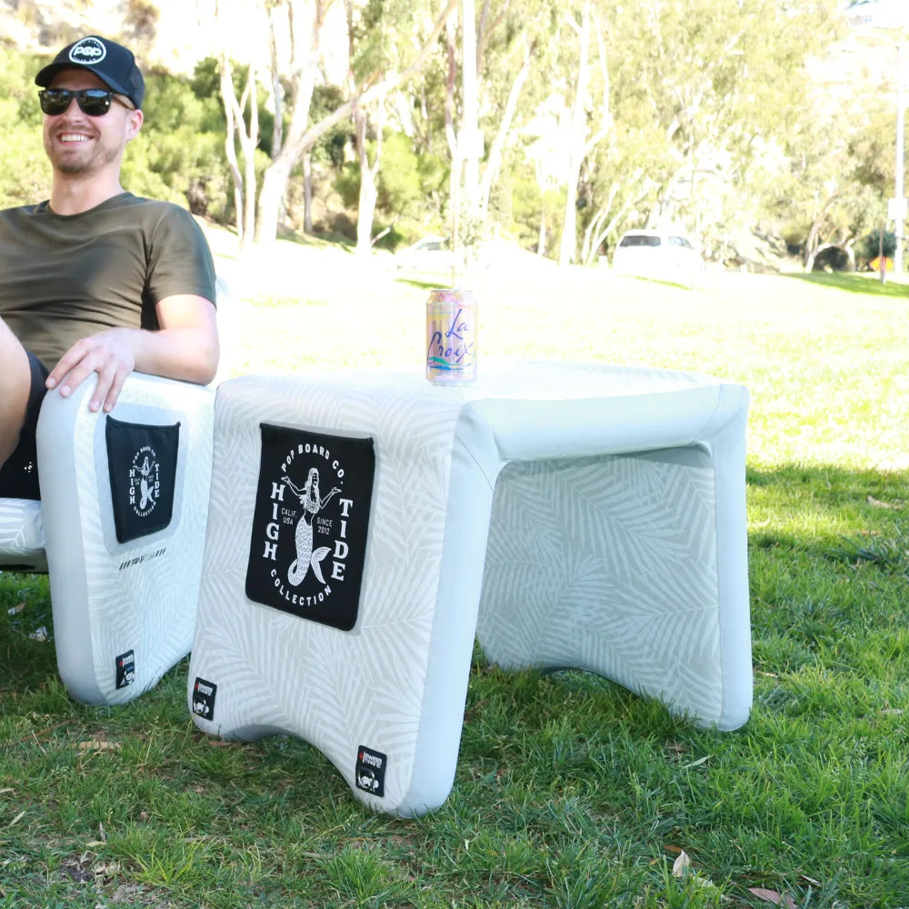 Man relaxing outdoors on POP inflatable chair with matching inflatable table holding a drink can.