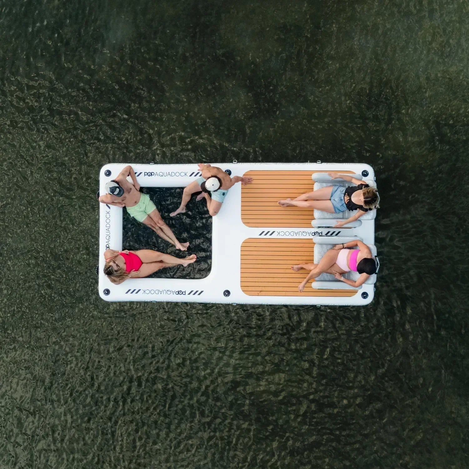 Overhead view of four friends relaxing on a POP Aquadock inflatable floating platform, enjoying time together on the water.