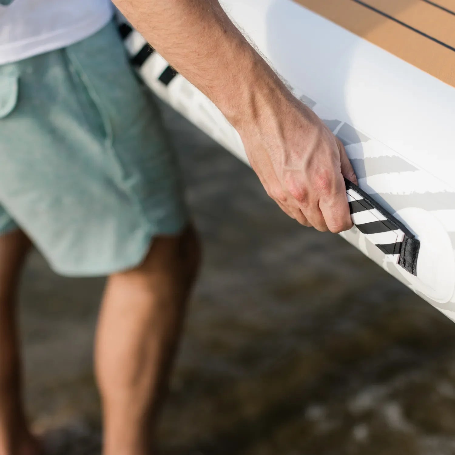 Close-up of a man holding the reinforced carry handle of a POPUP Dock inflatable platform, showing durable stitching and textured grip design.