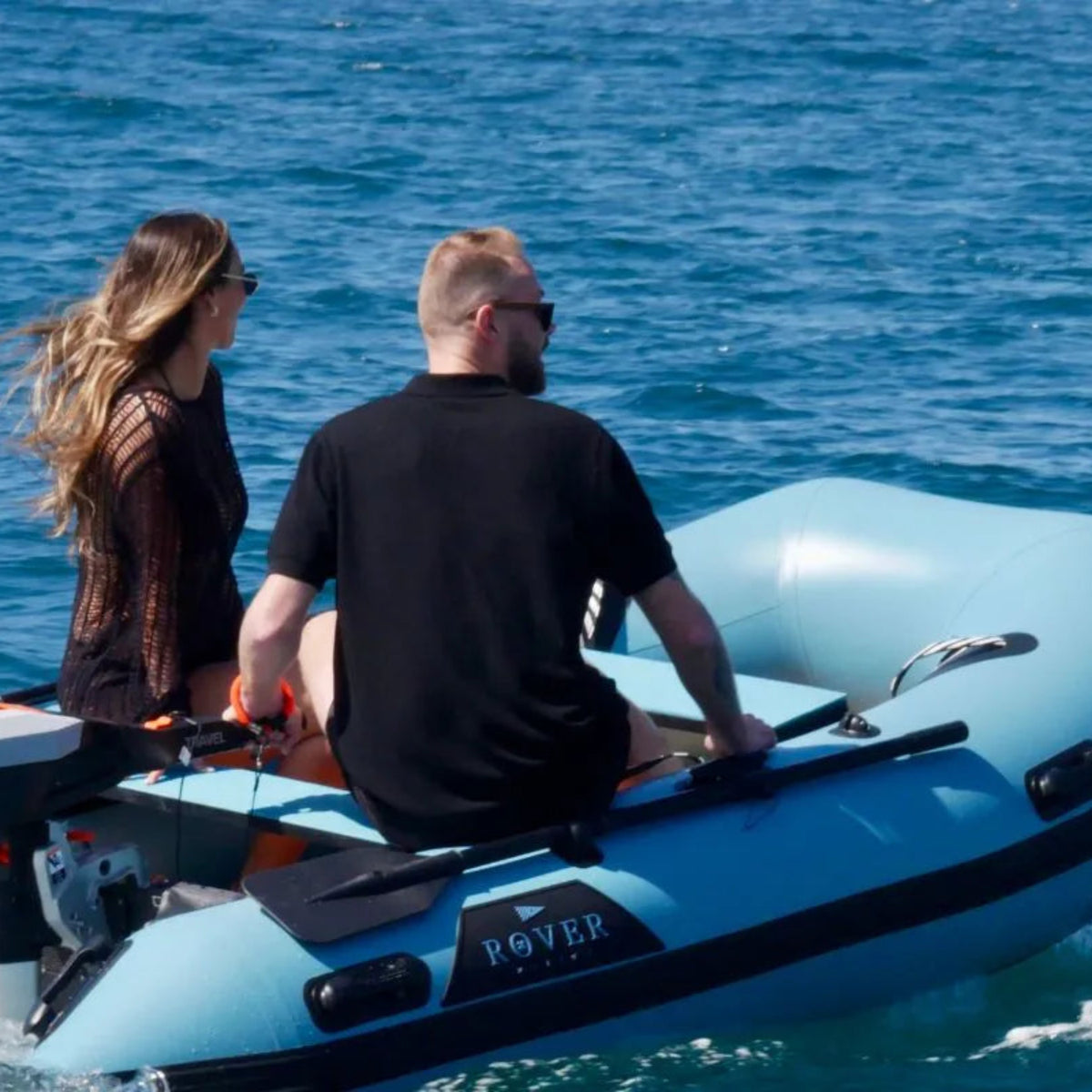 Two people on a blue inflatable boat in the water