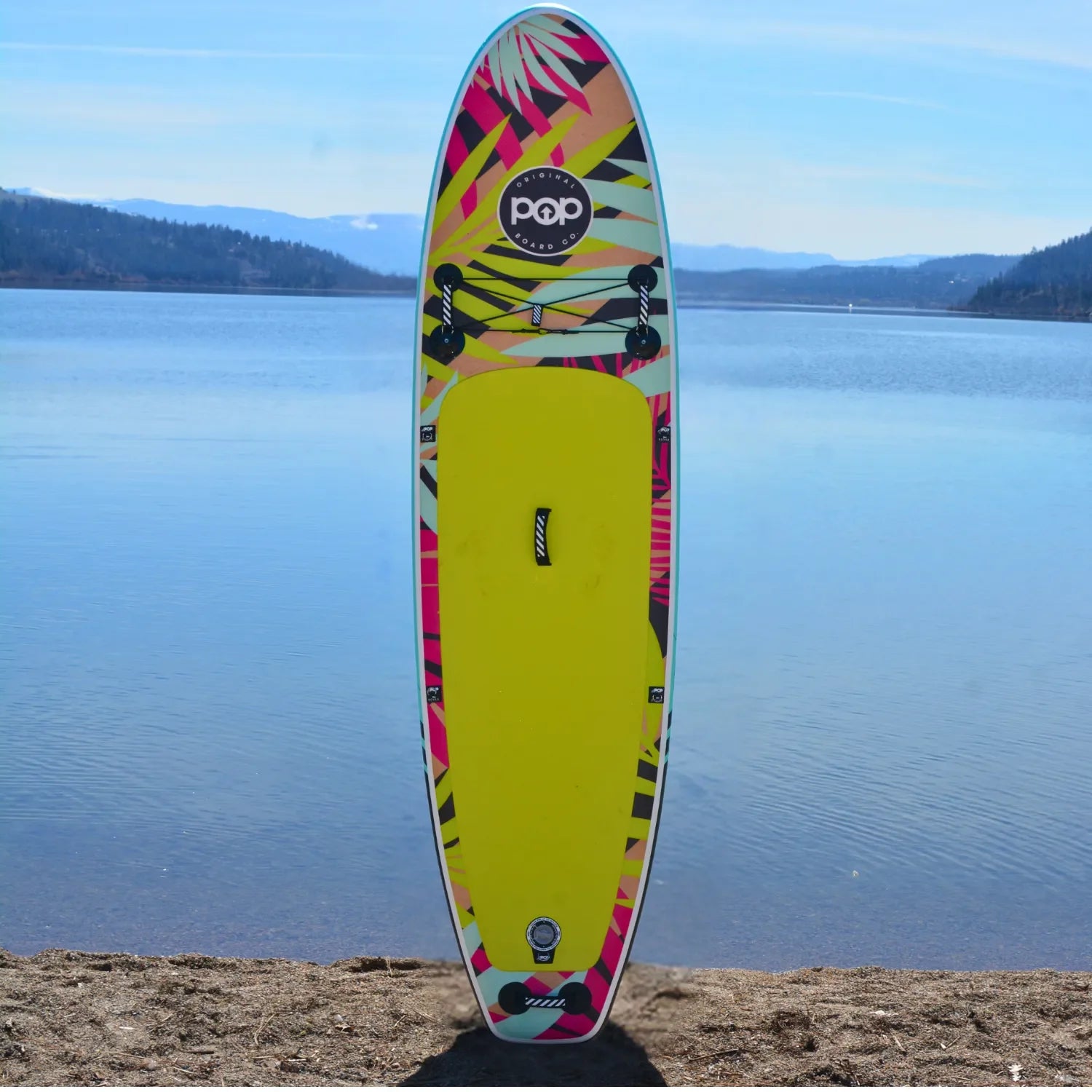 POP Royal Hawaiian 10’6 inflatable paddleboard 2024 standing upright by the lake with tropical graphics.