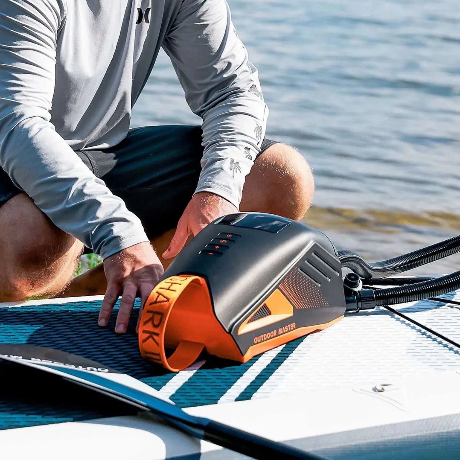 Shark 3 Electric Pump inflating a paddleboard by the water.
