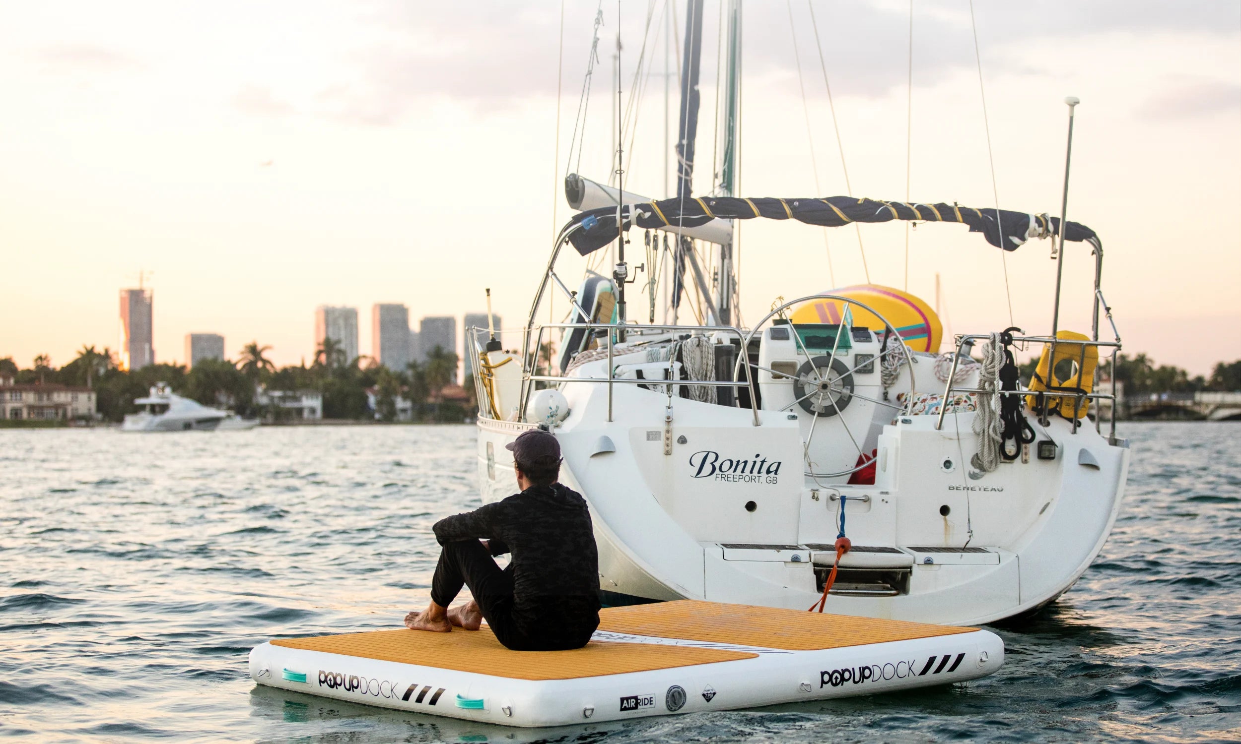Person relaxing on a used POP Up Dock from the Green Program, tethered to a yacht at sunset.