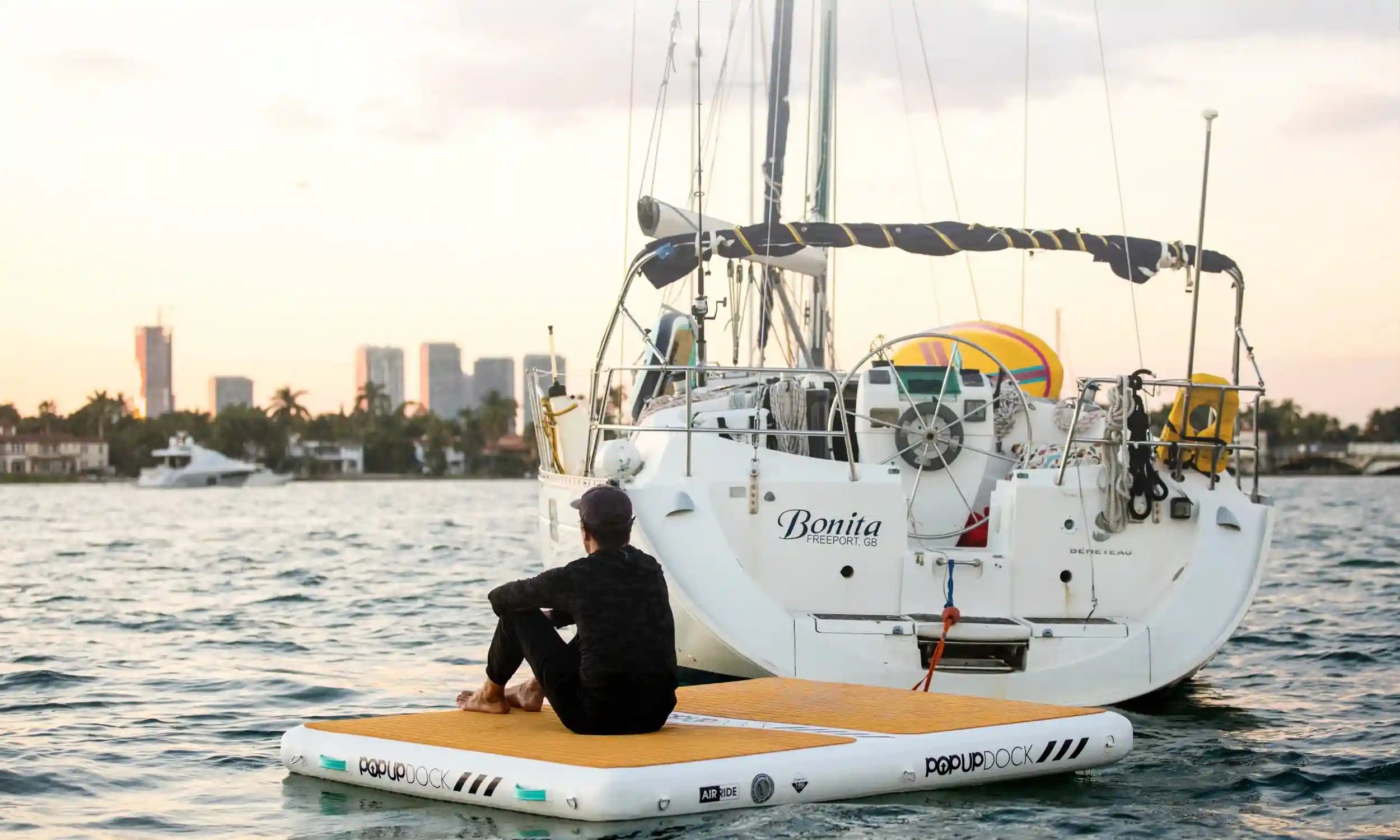 Person relaxing on a used POP Up Dock from the Green Program, tethered to a yacht at sunset.