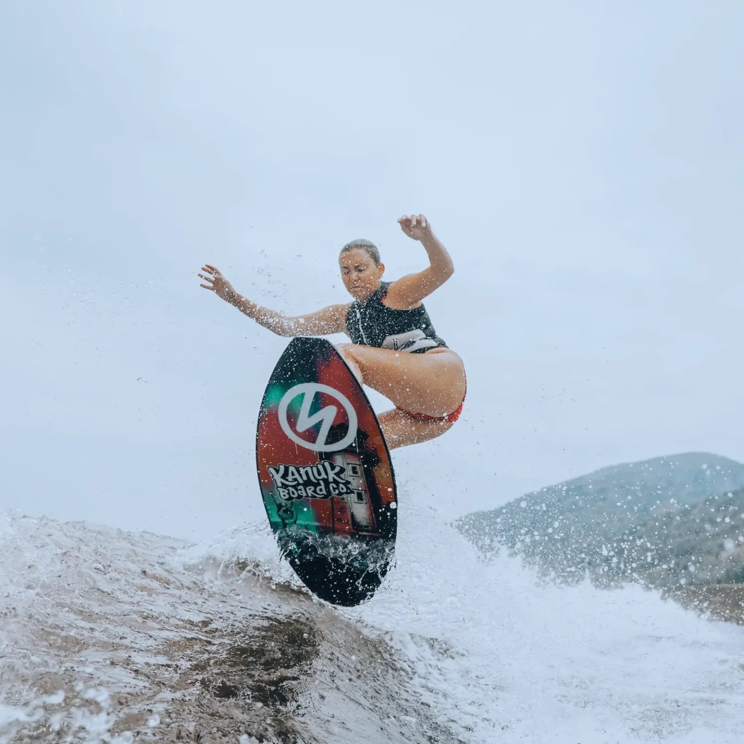 Female surfer smiling while carving waves on Vedder Sara Pro wakeskim board.