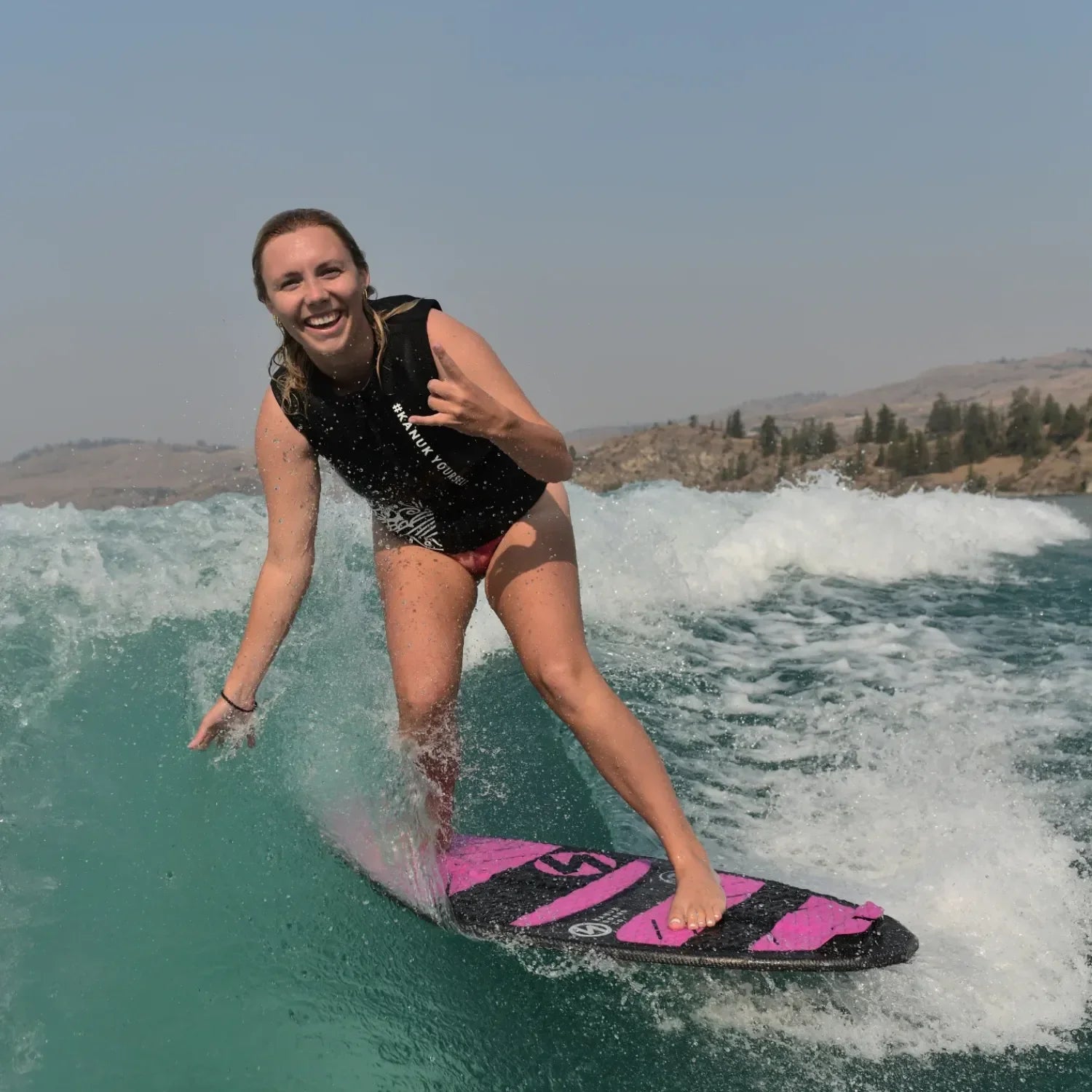 Female surfer smiling while carving waves on Vedder Sara Pro wakeskim board.