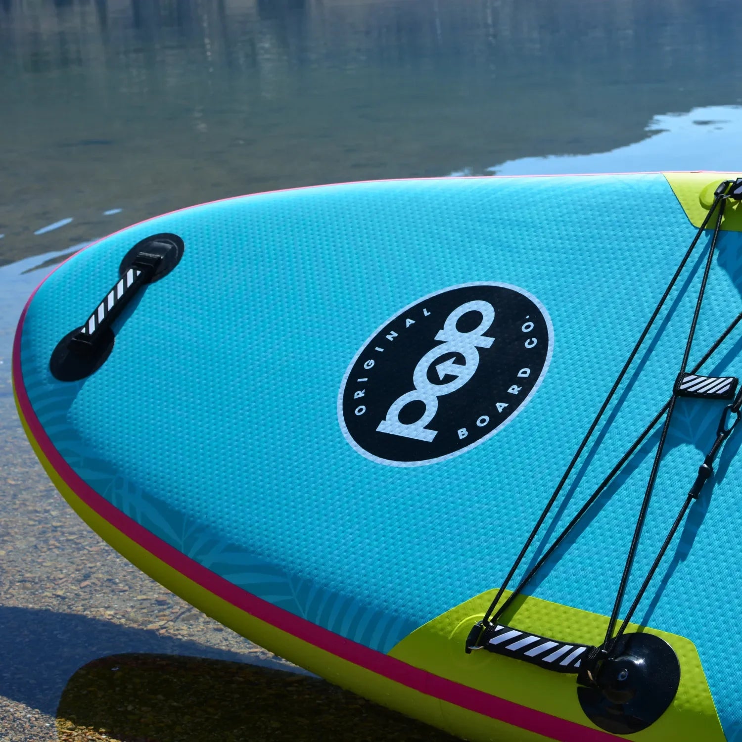 Nose detail of POP Yacht Hopper 11'0 inflatable paddleboard in turquoise, pink, and yellow on the water.