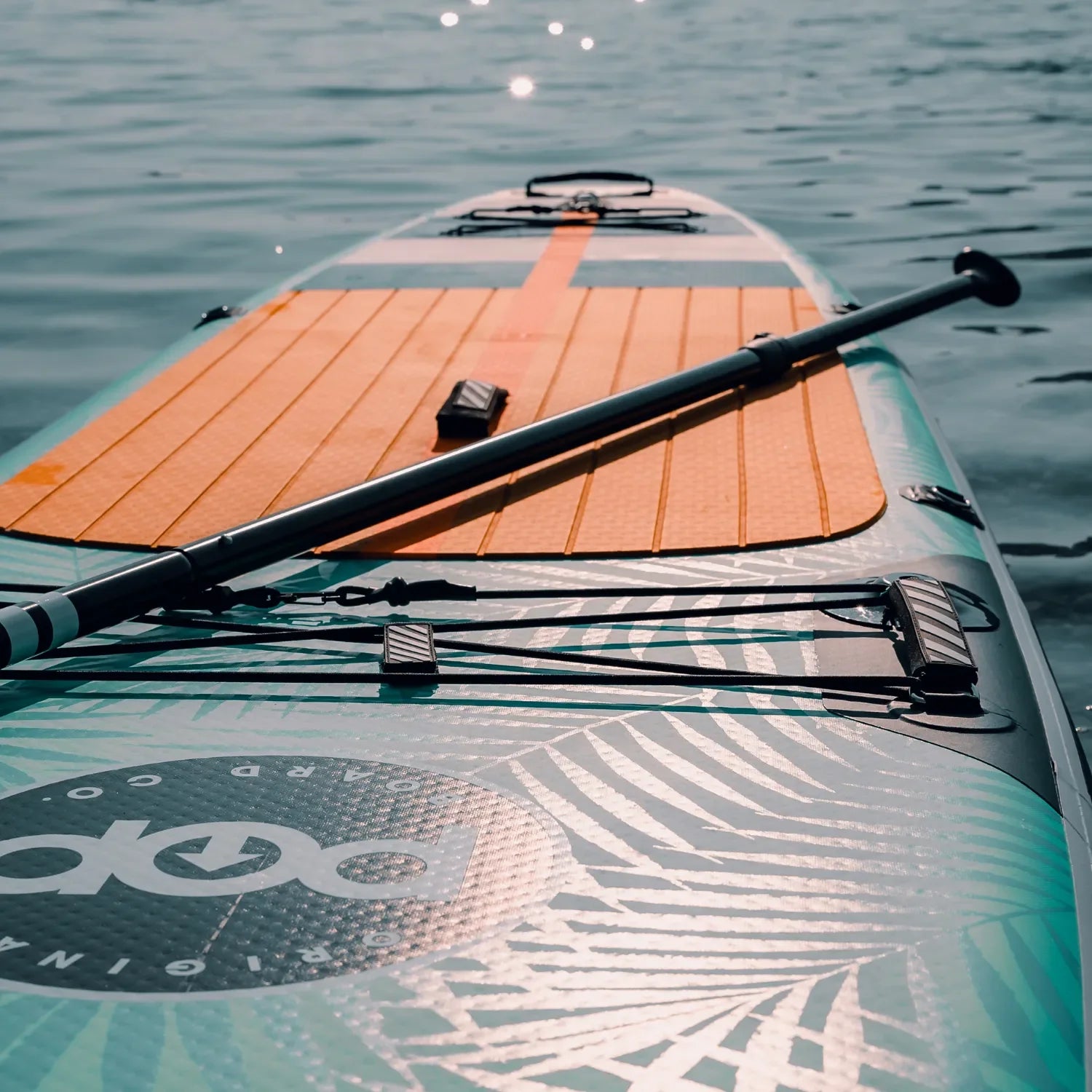 POP Yacht Hopper 11'0 inflatable paddleboard in teak blue and mint floating on calm water.