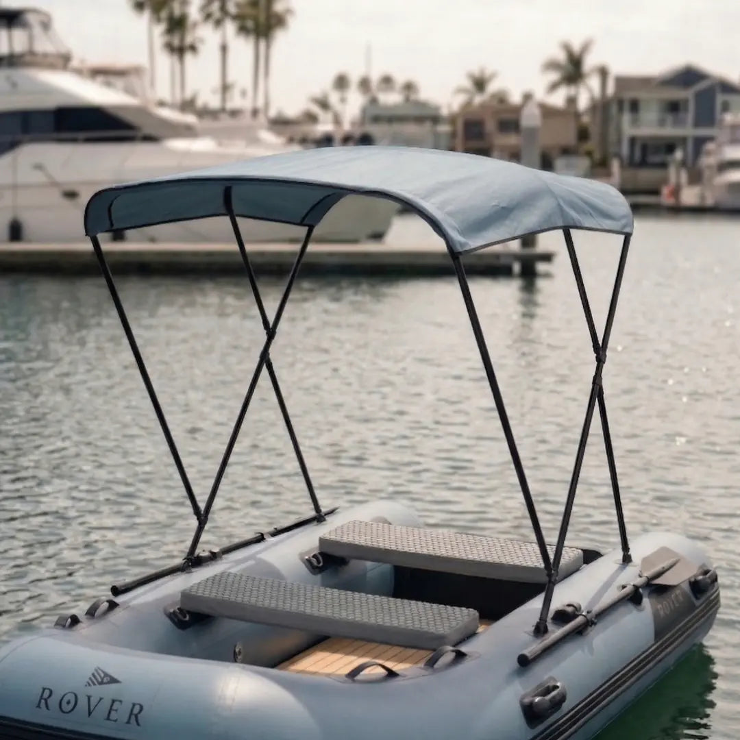 Inflatable boat with a canopy on a body of water with buildings and palm trees in the background.