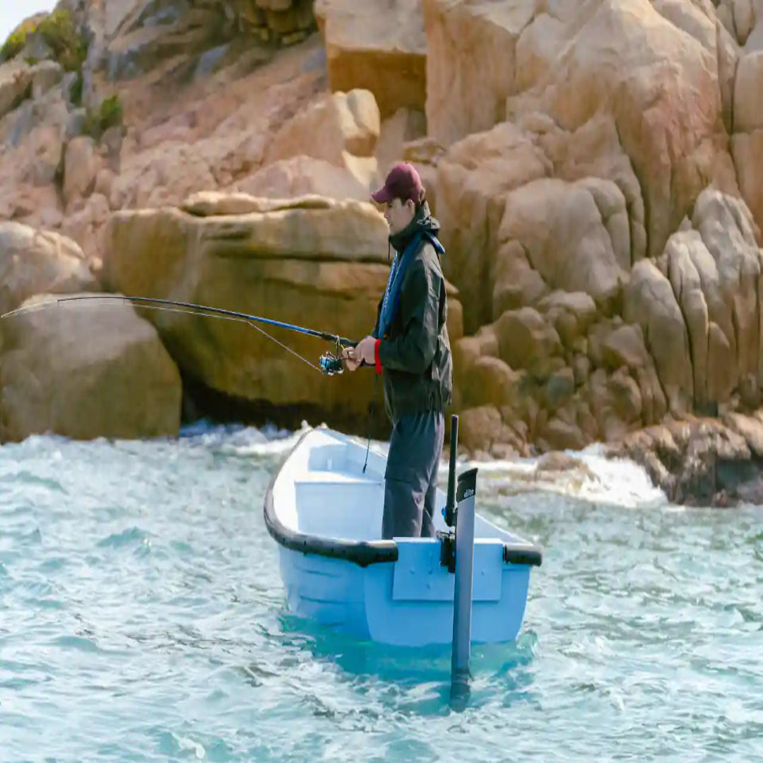 Person fishing from a small boat in a rocky coastal area