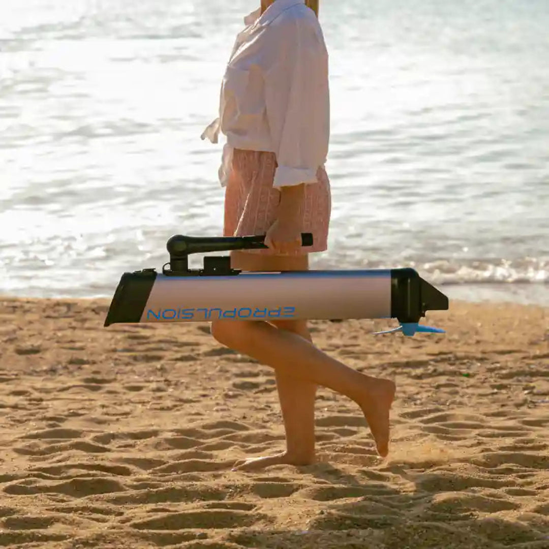 Person walking on a beach with a  electric motor labeled 'EPropulsion' in the foreground.