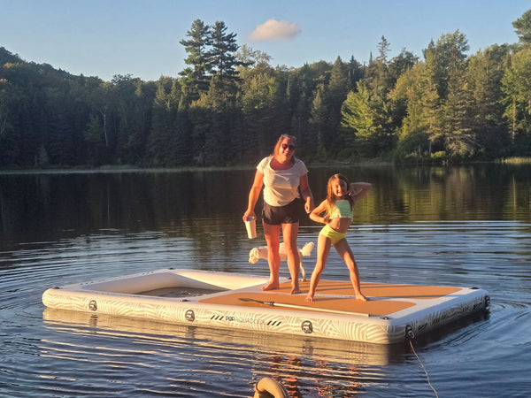 Mother and daughter standing on the AquaDock on a forested lake