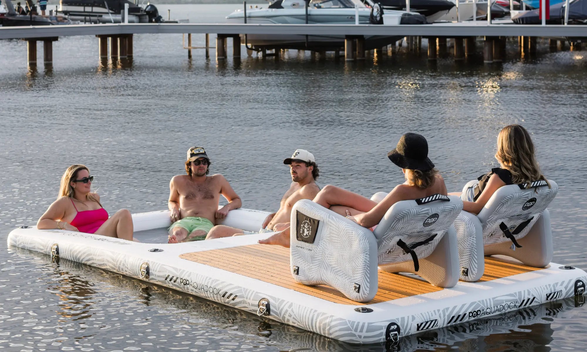 Group relaxing on POP AquaDock inflatable dock with chairs on the water.