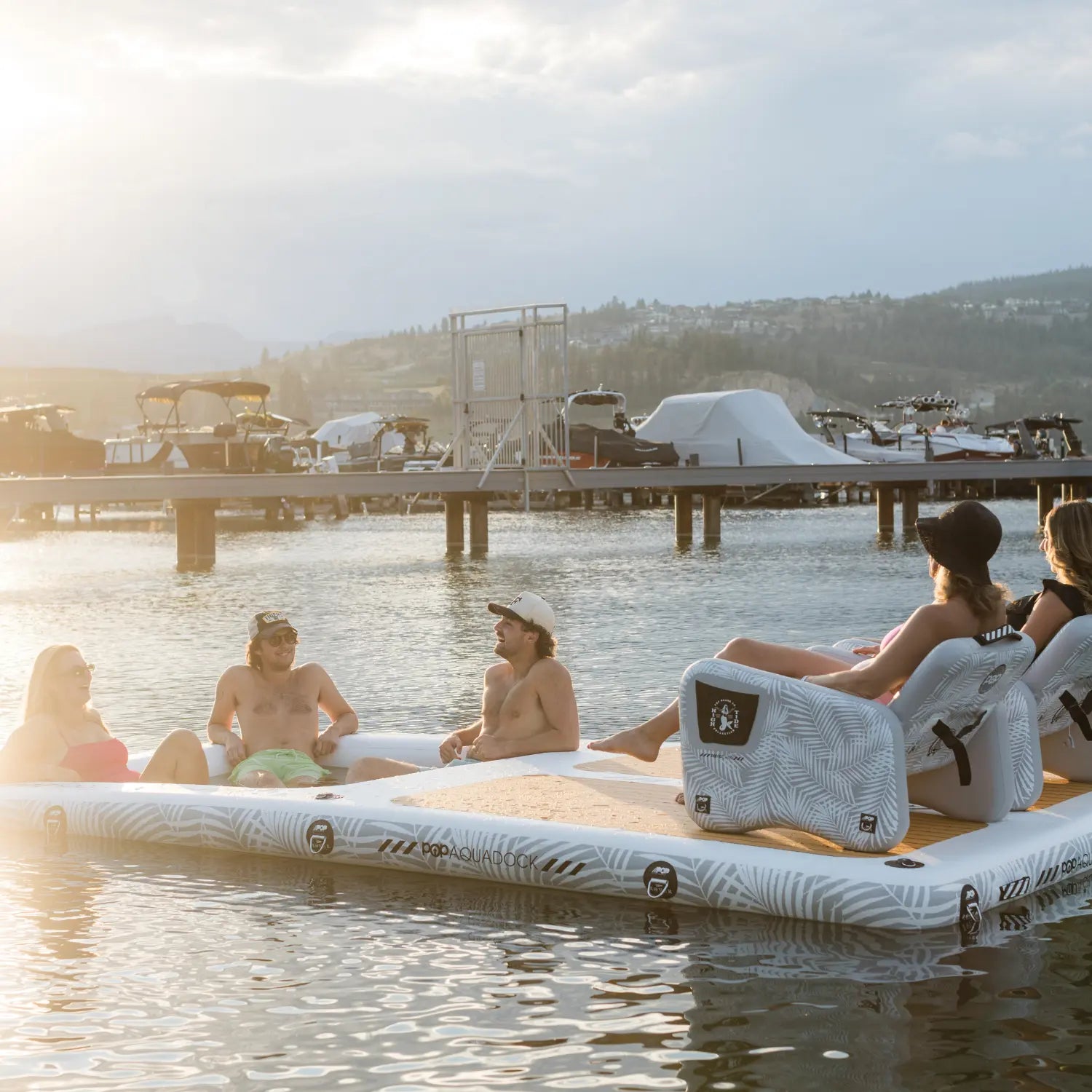 Friends enjoying sunset on POP AquaDock floating dock with teak traction pad.
