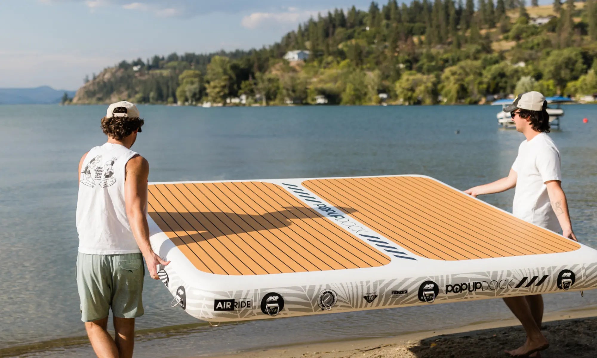Two men carrying the POP inflatable dock by the lake, showing portability and easy setup.