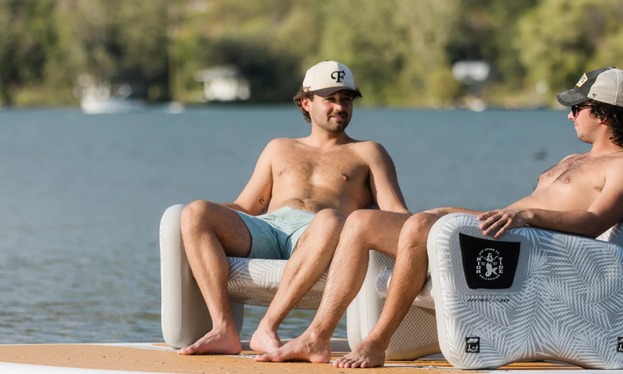 Two men relaxing on inflatable chairs placed on the POP Up Dock floating platform.