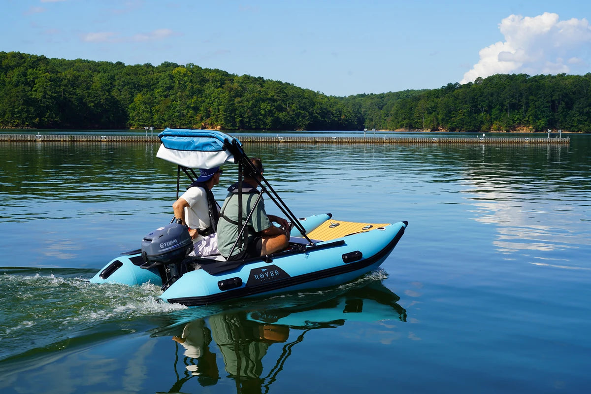Two people cruising a lake in a 10 ft Rover Marine Battle Cat inflatable catamaran with a Bimini top