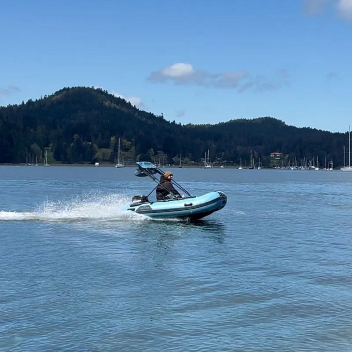 Person in a small inflatable boat on a lake with mountains in the background